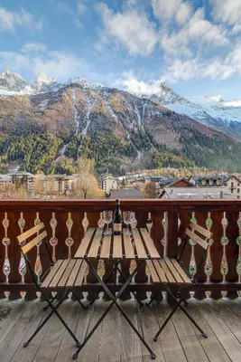 a wooden table on a balcony with a mountain at Apartment Rebats - Alpes Travel - Central Chamonix in Chamonix-Mont-Blanc