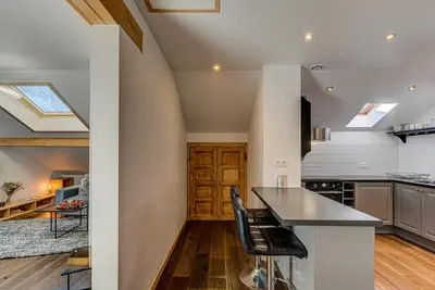 an attic kitchen with a black counter top and chairs at Apartment Rebats - Alpes Travel - Central Chamonix in Chamonix-Mont-Blanc