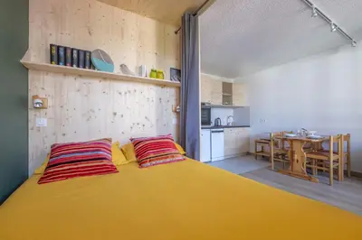 a bedroom with a large yellow bed with red pillows at Studio a l’aiguille du Midi in Chamonix-Mont-Blanc