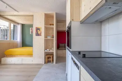 a room with a kitchen with a bed in the background at Studio a l’aiguille du Midi in Chamonix-Mont-Blanc