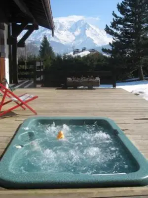 a hot tub on a deck with a snow covered mountain at Les Mules in Combloux
