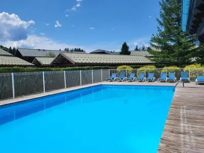 a swimming pool with chairs and a fence at Cascades, 3 bedroom chalet with shared pool. in Samoëns