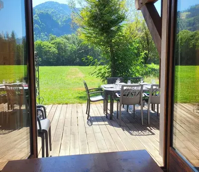 a patio with a table and chairs and a view of a field at Cascades, 3 bedroom chalet with shared pool. in Samoëns