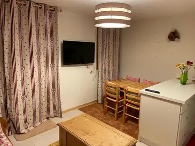 a kitchen and dining room with a table and a refrigerator at Studio montagne Demi Quartier in Demi-Quartier
