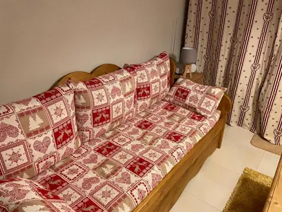 a couch with red and white cushions in a room at Studio montagne Demi Quartier in Demi-Quartier