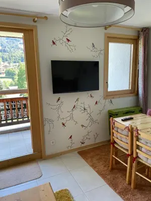 a living room with a flat screen tv on a wall at Studio montagne Demi Quartier in Demi-Quartier