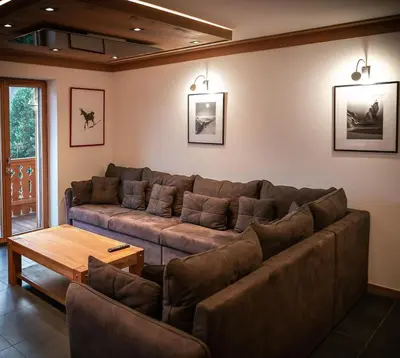 a living room with a large couch and a table at Les Ecureuils -Rénové 100m2 - 8per - Skis aux Pieds - Vue sur la Montagne in Les Houches