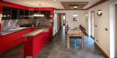 a kitchen with red cabinets and a wooden table at Les Ecureuils -Rénové 100m2 - 8per - Skis aux Pieds - Vue sur la Montagne in Les Houches