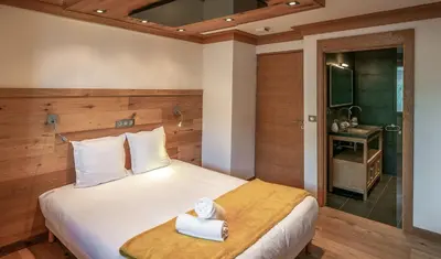 a bedroom with a bed with a towel on it at Les Ecureuils -Rénové 100m2 - 8per - Skis aux Pieds - Vue sur la Montagne in Les Houches