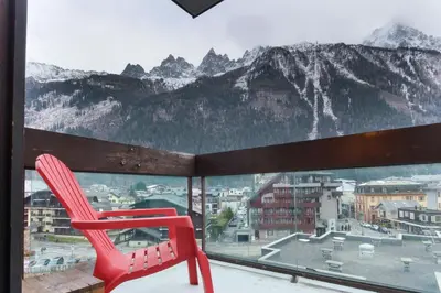 a red chair sitting on a balcony with a mountain view at L'Aiguille - Center of Chamonix - View Mont-Blanc in Chamonix-Mont-Blanc