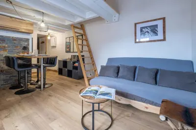 a living room with a blue couch and a ladder at Apt with nice view near the center of Chamonix in Chamonix-Mont-Blanc