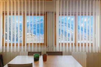 a dining room with a table and two windows at White Lodges - Megève center on ski slopes in Megève