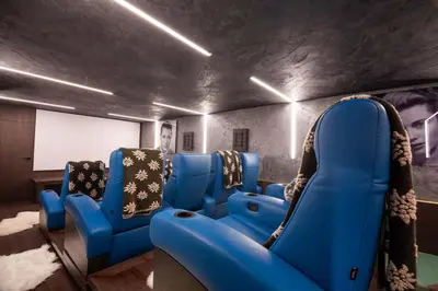 a cinema room with blue chairs and a white screen at Magic Megève Bois in Demi-Quartier