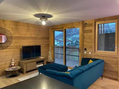 a living room with a blue couch and a television at les Airelles 202 in Les Carroz d'Araches