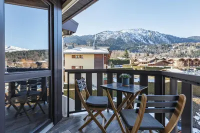 a table and chairs on a balcony with a view at Le Nid d'Aigle - Modern Apartment Next to Ski lift Prarion - By Cozee Rentals in Les Houches
