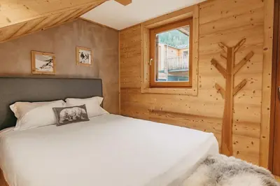 a bedroom with a white bed and a window at Chalet Isabella by Brennus Chamonix in Chamonix-Mont-Blanc