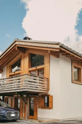 a house with a balcony and a car parked in front of it at Chalet Isabella by Brennus Chamonix in Chamonix-Mont-Blanc