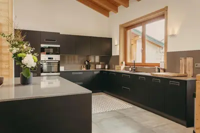 a kitchen with black cabinets and a vase of flowers at Chalet Isabella by Brennus Chamonix in Chamonix-Mont-Blanc