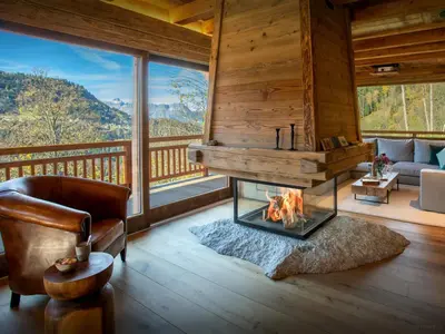 a living room with a fireplace in a log cabin at Chalet Beau Caillou - OVO Network in Saint-Gervais-les-Bains