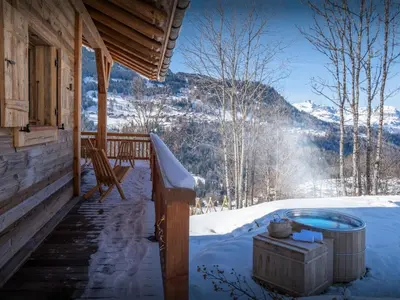 a hot tub on the porch of a cabin in the snow at Chalet Beau Caillou - OVO Network in Saint-Gervais-les-Bains