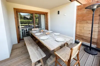 a wooden table and chairs on a wooden deck at Les Chamois D’Arbois, Mont D’Arbois, Megève in Megève