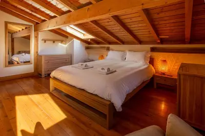 a bedroom with a large bed in a room with wooden floors at Chalet des Favrands in Chamonix-Mont-Blanc