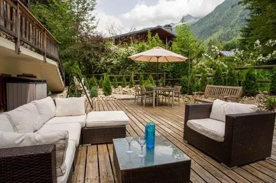 a patio with a couch and chairs and an umbrella at Chalet des Favrands in Chamonix-Mont-Blanc