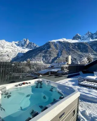 a hot tub on a balcony with snow covered mountains at Appartement Rooftop Chamonix in Chamonix-Mont-Blanc