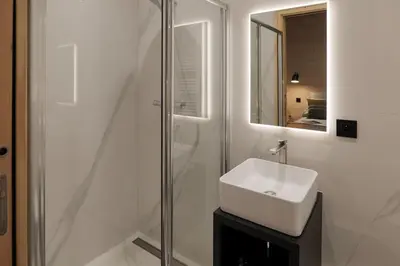a white bathroom with a sink and a shower at Appartement Rooftop Chamonix in Chamonix-Mont-Blanc