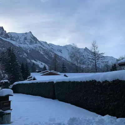 a fence covered in snow with mountains in the background at Belle Vue Des Praz in Chamonix-Mont-Blanc