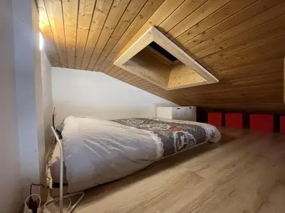 a bed in a room with a wooden ceiling at Chaleureux 3 pièces + mezzanine, 6/7 pers, poêle à bois, balcon ouest, parking, proche centre et pistes - FR-1-572-271 in Arâches-la-Frasse