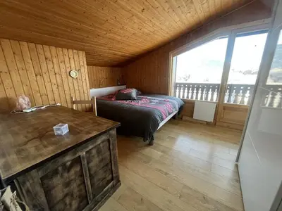 a bedroom with a bed and a large window at Chaleureux 3 pièces + mezzanine, 6/7 pers, poêle à bois, balcon ouest, parking, proche centre et pistes - FR-1-572-271 in Arâches-la-Frasse