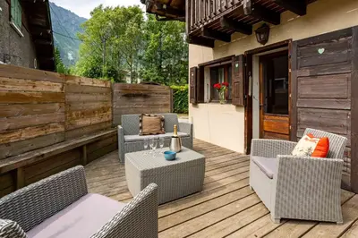a patio with chairs and tables on a wooden deck at Chalet le Tremplin in Chamonix-Mont-Blanc