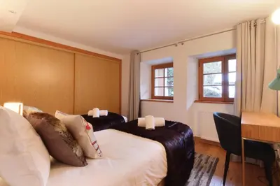 a hotel room with two beds and a desk at Les Alpins - Centre de Chamonix - Rénové avec Jardin et vue imprenable sur le MontBlanc in Chamonix-Mont-Blanc