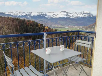 a table and chairs on a balcony with snow covered mountains at Apartment Le Domaine de Crespin by Interhome in Saint-Gervais-les-Bains