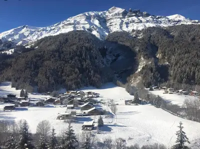 a small village in the snow in front of a mountain at Cozy studio au centre du village & superbe vue in Les Contamines-Montjoie