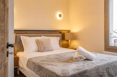 a bedroom with a bed with white sheets and a window at Perle Blanche - Brand New 2 bedroom apartment perfectly located in Chamonix-Mont-Blanc