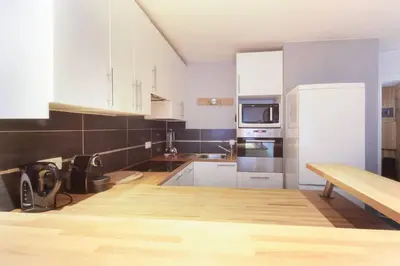 a kitchen with white cabinets and a wooden table at L'Outa - Center of Chamonix - Mont-Blanc view in Chamonix-Mont-Blanc