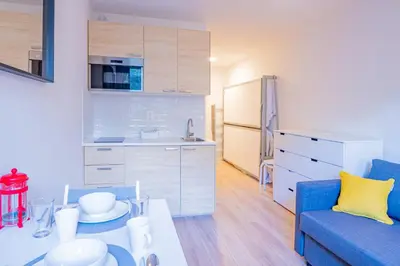 a living room with a blue couch and a kitchen at Forclaz River 1- Beautifully crafted Studio in Chamonix-Mont-Blanc