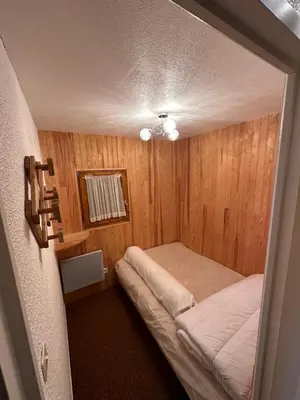 a small bedroom with a bed in a room with wooden walls at Appartement Les Carroz d'Araches 4 à 6 couchages, vue sur montagne in Les Carroz d'Araches
