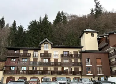 a large building with cars parked in a parking lot at Appartement Les Carroz d'Araches 4 à 6 couchages, vue sur montagne in Les Carroz d'Araches