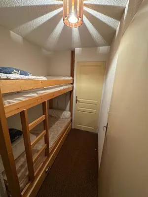 a small room with a bed and a chandelier at Appartement Les Carroz d'Araches 4 à 6 couchages, vue sur montagne in Les Carroz d'Araches