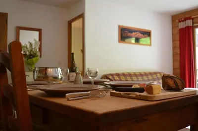 a wooden table with plates and wine glasses on it at 2 bedroom Apartment in Les Houches Stone's throw from Prairon lift in Les Houches