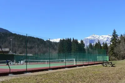 a tennis court with snowy mountains in the background at 2 bedroom Apartment in Les Houches Stone's throw from Prairon lift in Les Houches