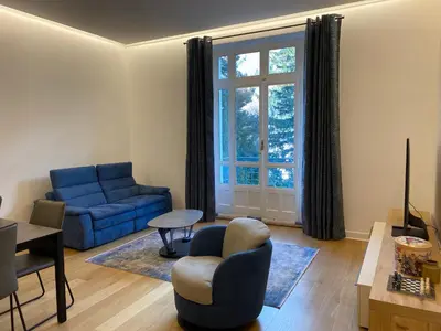 a living room with a blue couch and a window at Chamonix - Majestic vue Mont Blanc in Chamonix-Mont-Blanc