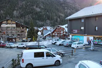 a group of cars parked in a parking lot in front of buildings at Les Pierres Blanches Contamines Montjoie in Les Contamines-Montjoie