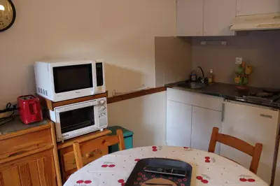 a kitchen with a microwave oven and a table with a table at Les Pierres Blanches Contamines Montjoie in Les Contamines-Montjoie