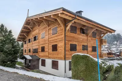 a large wooden building with snow on the ground at Appartement Périade - Welkeys in Megève