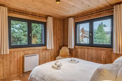 a bedroom with a bed and two windows at Appartement Périade - Welkeys in Megève