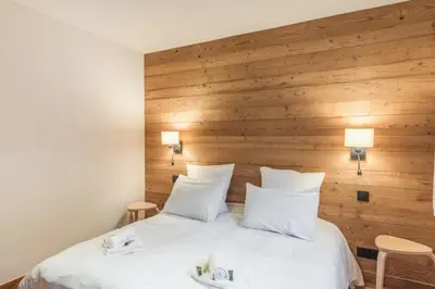 a bedroom with a large white bed with wooden walls at Appartement Périade - Welkeys in Megève